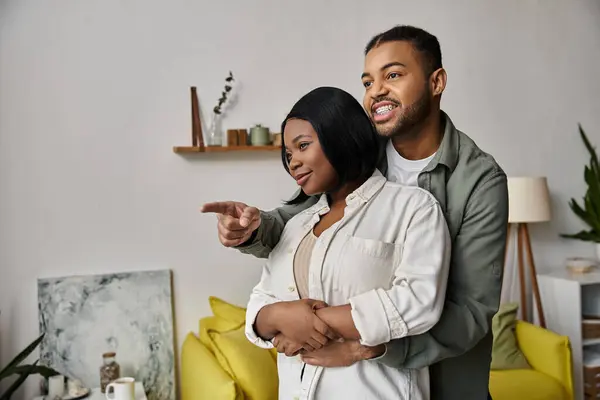 stock image A african american couple embraces, pointing towards shared dreams and a hopeful future.