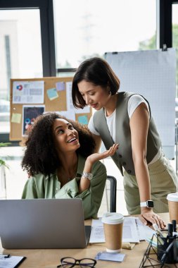 Modern ofiste masabaşında çalışan lezbiyen çift gülümsüyor..