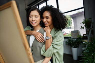 A lesbian couple working together and hugging in office. clipart