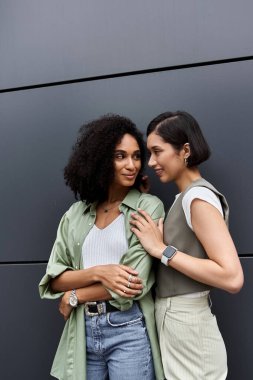 Two women, a lesbian couple, stand close together outside. clipart