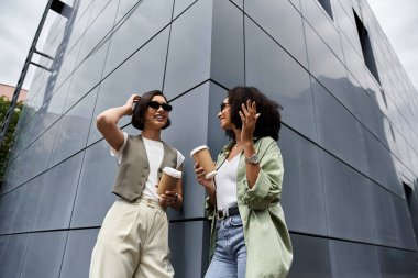 Birbirine aşık iki kadın binanın dışında kahve molası veriyor..