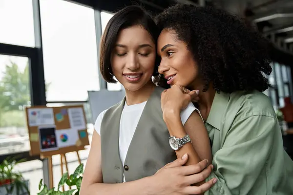stock image Two women in a loving relationship share a tender moment in the office.