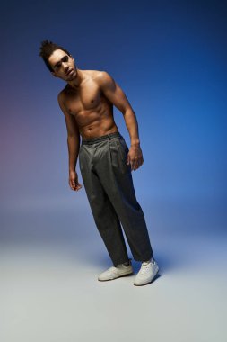 A young African American man dances in front of a vibrant, gradient background. He wears grey pants and white sneakers. clipart