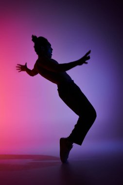 Genç Afrikalı Amerikalı bir adamın silüeti canlı, renkli bir arka plana karşı dans ediyor..