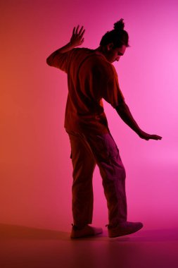 Genç bir Afrikalı Amerikalı, renkli bir arka plana karşı dans ediyor..