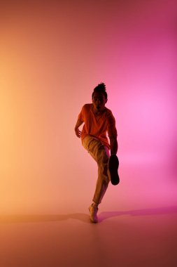 Afrikalı Amerikalı bir erkek dansçı renkli bir arka plana karşı dinamik bir hareket sergiliyor..