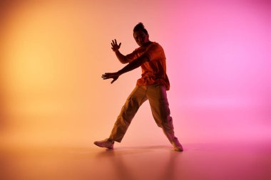 Genç bir Afrikalı Amerikalı, renkli bir geçmişi olan bir stüdyoda dans ediyor..