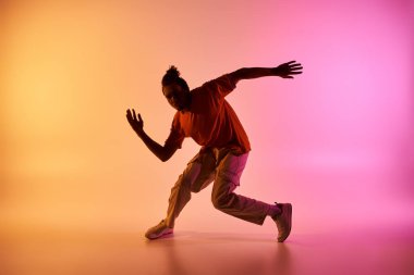 Genç bir Afrikalı Amerikalı erkek dansçı bir stüdyoda değişken bir geçmişe karşı hip-hop dansı yapıyor..
