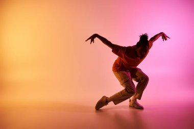 A young African American man dances on a colorful gradient background, showcasing his skill and passion for movement. clipart