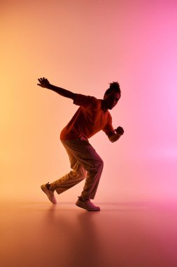 A young African American man dances with energetic moves against a colorful gradient background. clipart