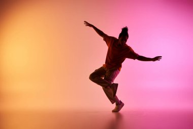 A young African American male dancer executes a move in a vibrant studio setting with a colorful gradient background. clipart