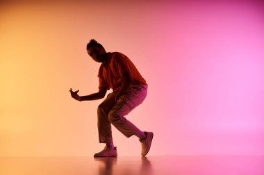 A young African American male dancer performs a move on a colorful gradient background. clipart