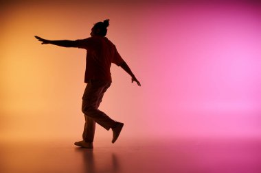 A young African American man dances in silhouette against a backdrop of a colorful gradient. clipart