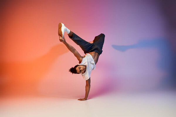 A young African American man dances on a gradient background, showcasing his impressive skills.