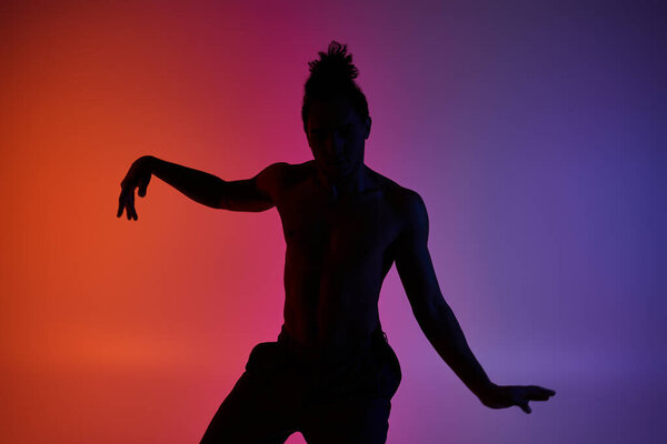 Silhouette of a young African American man dancing against a vibrant neon background.