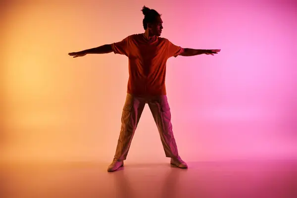 stock image A young African American man dances on a stage lit by pink and yellow neon lights.