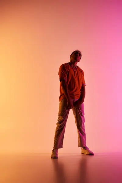 Stock image An African American male dancer poses against a vibrant gradient background, illuminated by colorful lighting.