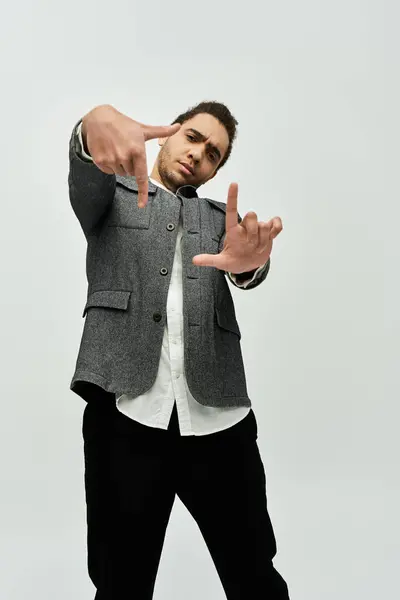 stock image A stylish African American man in a gray coat and black pants poses against a white background.