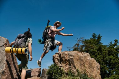 A young gay couple hikes together in the wilderness on a sunny summer day. clipart