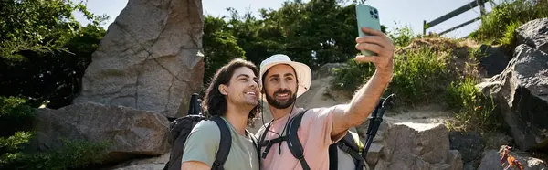 stock image A young gay couple takes a selfie while hiking in a summer wilderness setting.