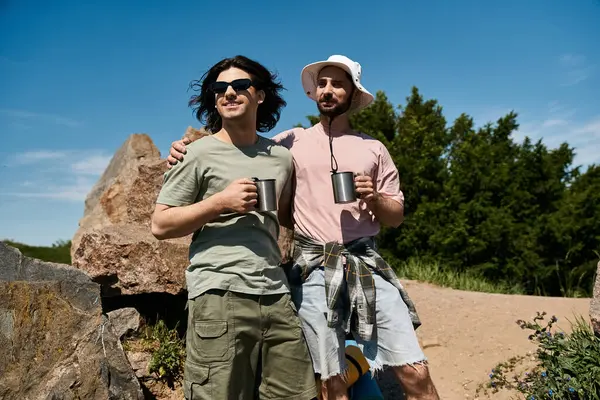 stock image A gay couple enjoys a summer hike together, stopping for a moment to admire the view and share a drink.