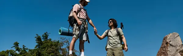 stock image A young gay couple hikes together in a sunny, outdoor wilderness setting.