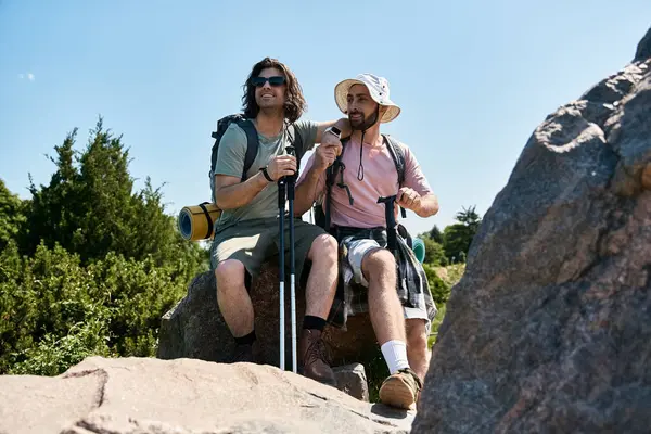 stock image A gay couple enjoys a summer hike, resting on a rocky outcrop in the wilderness.