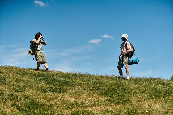 Двое молодых людей, гей-пара, прогуливаются вместе в солнечный летний день в районе дикой природы.