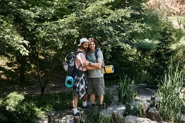 stock image Two young men hike through a summer forest, embracing each other and smiling.