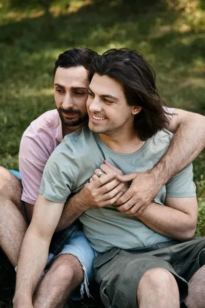 stock image A young gay couple embraces in a field of green grass during a summer hike.