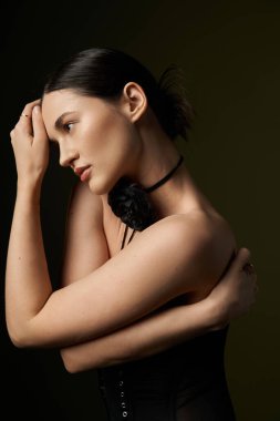 Siyah saçlı ve çiçekli bir kadın siyah arka planda poz veriyor..