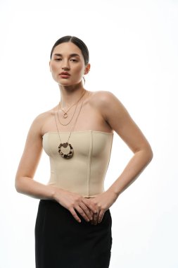 A young woman in a cream top showcases a collection of necklaces with a white backdrop. clipart