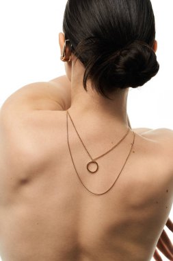 A young woman displays her elegant gold necklace on a white backdrop. clipart