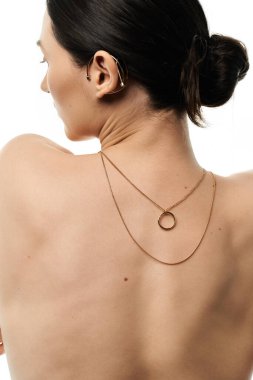 A woman shows off a gold necklace with a circle pendant. clipart