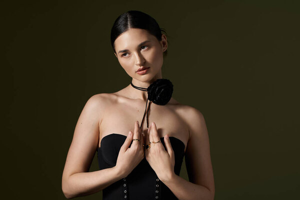 Молодая женщина с темными волосами и цветочным шокером позирует на темном фоне, подчеркивая ее красоту и элегантность..