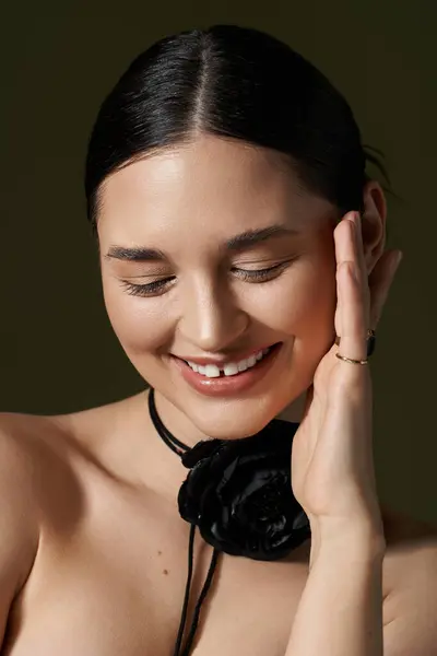 stock image A beautiful young woman with brunette hair and a black flower choker poses against a dark background.