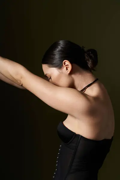 Stock image A young woman with brunette hair poses against a black background