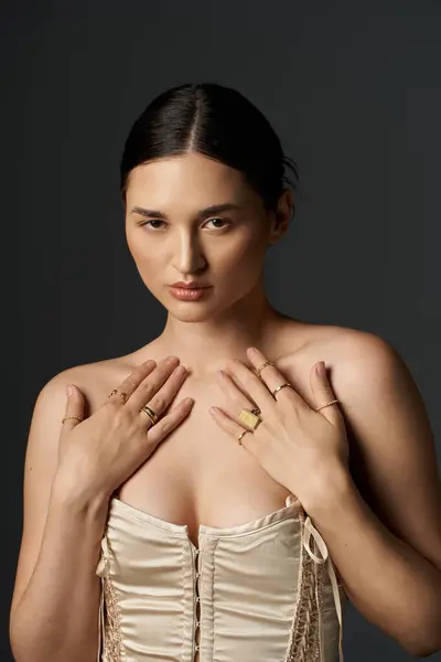 stock image A young woman with dark hair shows off her golden rings on her fingers against a dark background.