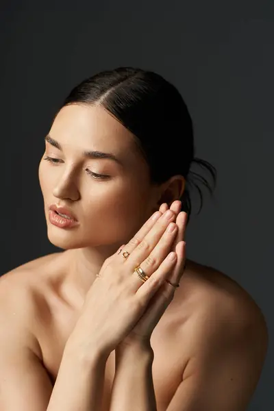 stock image A young woman with dark hair shows off her gold rings against a dark background.