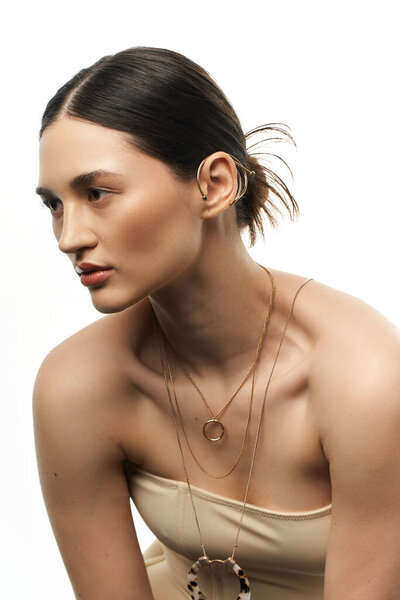 Молодая женщина с брюнетками носит роскошные украшения на белом фоне.