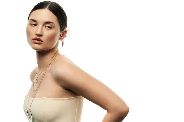 stock image A young brunette woman with flawless skin displays a collection of exquisite jewelry against a white background.