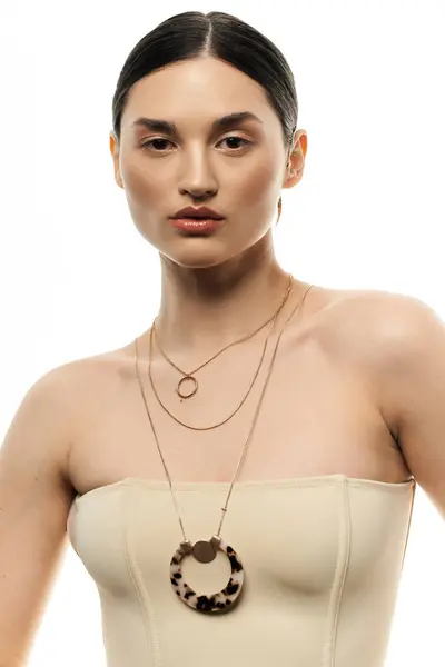 stock image A brunette woman displays her layered jewelry elegantly against a white background, exuding timeless fashion.