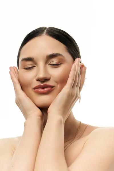 stock image A young brunette woman poses with her eyes closed, showcasing beautiful jewelry against a white background.