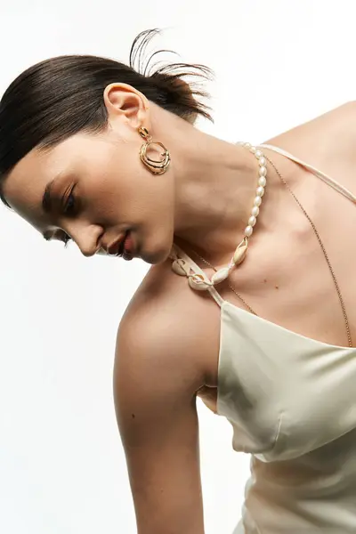 stock image A young brunette woman showcases delicate, elegant jewelry against a white backdrop, capturing the essence of beauty and fashion.