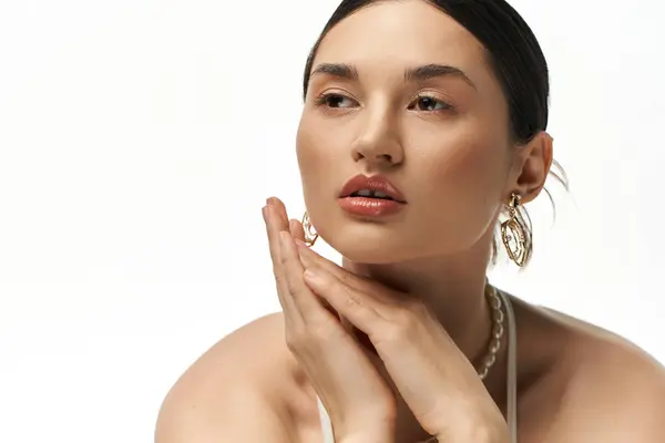 stock image A young woman with hands clasped under chin, displaying jewelry against white backdrop.