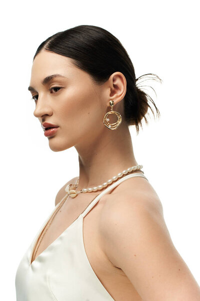 A young woman with dark hair is shown wearing gold earrings and a pearl necklace, showcasing her beautiful and luxurious jewelry.