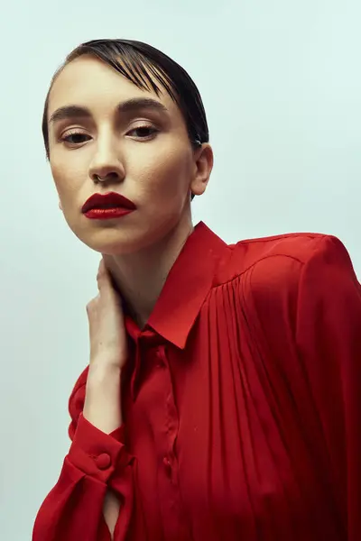 stock image A young woman with short, wet hair poses in a red shirt, creating a captivating fashion image.