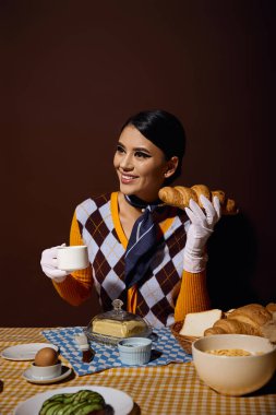 Kahvaltı masasında kahve ve kruvasanla şık bir kadın..