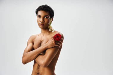 A young, muscular African American man adorned with flowers poses against a grey background. clipart