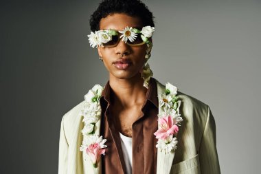 Genç bir Afrikalı Amerikalı, çiçeklerle süslenmiş şık bir ceketle poz veriyor. Güzellik ve çeşitliliğe benzersiz ve modern bir bakış açısı sergiliyor..